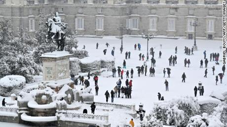 People enjoy the snow outside the Royal Palace in Madrid on January 9, 2021.